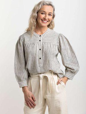 Natural-toned striped blouse with black buttons, featuring gathered details at the yoke, emphasizing Colouron Cotton's slow fashion values.