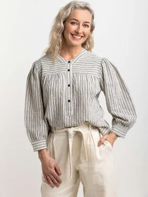 Natural-toned striped blouse with black buttons, featuring gathered details at the yoke, emphasizing Colouron Cotton's slow fashion values.