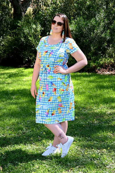 Woman wearing a green and blue dress with a colorful abstract print featuring fruit and ice-cream illustrations, styled for a playful, sunny-day look. Christmas haul